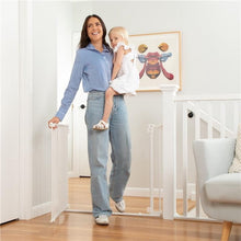 White baby safety gate at doorway, child held beside the barrier