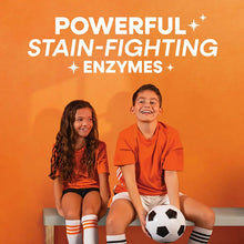 Two children sitting smiling beside a soccer ball on a detergent promo scene