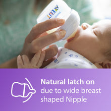 Natural baby bottle in white held near a baby’s mouth