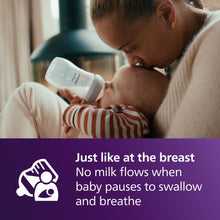 Philips Avent Natural baby bottle with white nipple during feeding, baby held close