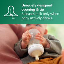 Baby holding a clear glass baby bottle with white nipple for feeding