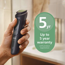 Black handheld trimmer with green blade detail held in a hand