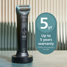 Body groomer trimmer with teal foil head, black handle, and charging stand base