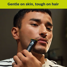 Electric face shaver held to the chin, black OneBlade trimmer for facial hair