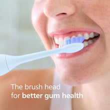Replacement brush head brushing teeth with soft blue bristles on a white handle