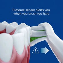 Sonic toothbrush bristles near teeth with pressure sensor indicator arrow