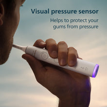 White sonic toothbrush with blue-lit bristles held in a hand