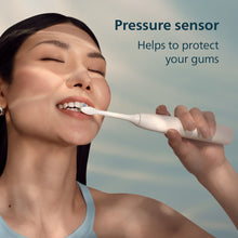Person brushing teeth with a white Philips Sonicare rechargeable toothbrush