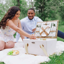 Open wicker picnic basket with lemon-print fabric and utensils on blanket
