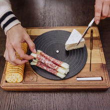 Acacia turntable cheese board with stacked cheeses, slicing knife, and dark round slate.