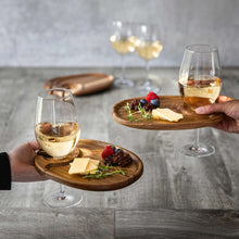 Wooden oval appetizer plates with handle notches on a table with wine glasses