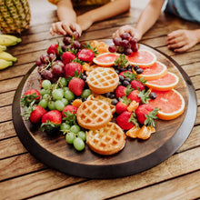 Acacia wood lazy Susan serving tray on table with fruit, waffle pieces, and herbs