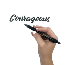 Hand holding a black gel roller pen while writing