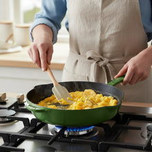 Green enameled cast-iron skillet on a gas burner, being used to cook food in a kitchen