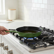 Green enameled cast-iron skillet on a gas stove with oil shimmering in the pan