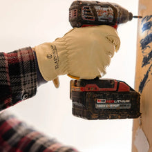 Tan leather glove with stitched logo patch, holding a cordless drill