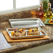 Aluminum 1/4-size baking sheet with two chicken portions on wooden board.