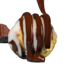 Caramel-coated zebra popcorn with white drizzle on a spoon