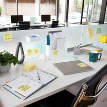 Canary yellow sticky notes on a white office desk with stationery