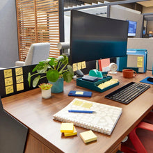 Canary yellow sticky notes on a wooden office desk with supplies