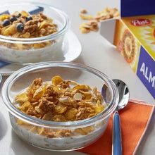 Glass bowls of oat cereal with honey and almonds, beside cereal box