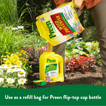Preen Garden weed preventer plus plant food refill bags held by person near garden plants