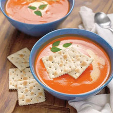 Saltine crackers with a square cutout and a dotted surface, served with orange dip