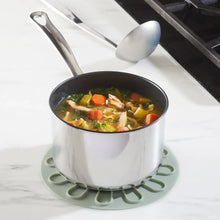 Silicone lid with circular vented pattern placed over a stainless pot