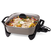 Ceramic electric skillet with glass lid and black handles, showing food inside