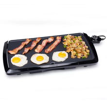 Presto electric griddle with bacon strips and sunny-side eggs on dark surface