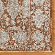 Area rug close-up with rust and gray repeating pattern and beige border on cream ground.