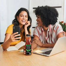 Unsweetened Pure Leaf tea bottle on table while friends use phones and laptops