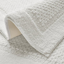 White bath rug with thick textured pile and folded corner detail