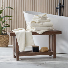 Cream towel set with folded bath towels and stacked hand towels on a wooden stand