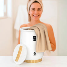 White towel warmer with wooden base, lid open, holding a beige towel