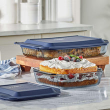 Tinted glass baking dishes with blue lids stacked, showing whipped dessert tops