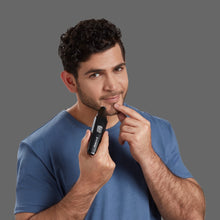 Men's trimmer grooming the face with guard attachment in hand