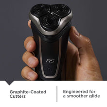 Hand holding REMINGTON R5 rotary shaver, three circular heads on black handle
