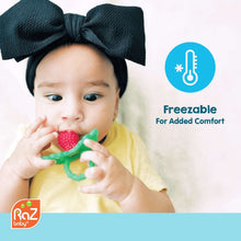 Silicone teether with red berry and green handles in baby's hands