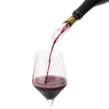 Wine pourer nozzle dispensing red wine into a glass, black handle