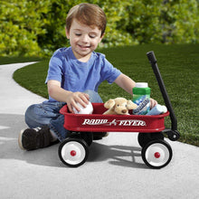 Red Radio Flyer mini wagon with boy seated and plush toy in front