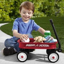 Child playing with red toy wagon on wheels, with stuffed animals in the tray