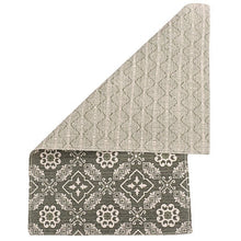 Reversible accent rug corner: beige top and dark gray bottom with white geometric motifs.