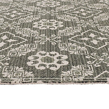 Close-up of dark gray woven rug with dense white geometric and floral patterning.