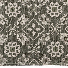 Close-up of charcoal and green-toned rug with large white floral and diamond motifs.