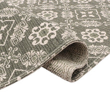 Accent rug edge view showing dark gray fabric with white repeating geometric motifs.