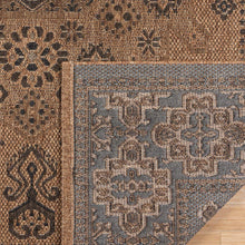 Indoor/outdoor rug corner detail: tan with blue-gray and dark geometric pattern