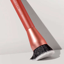 Round base makeup brush angled with dense black bristles on rose-gold handle