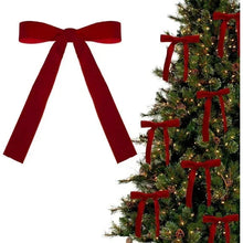 Red velvet Christmas bow with long tails displayed above a decorated tree with bows.