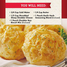 Cheddar biscuits close-up on a cloth with buttered, herb-speckled tops